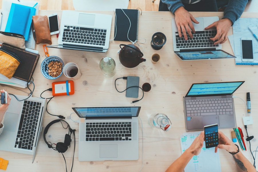 A team working side by side at a shared table of laptops